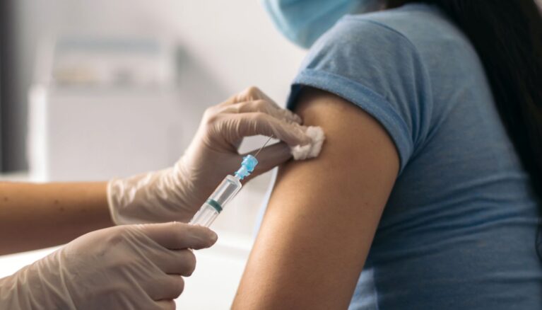 nurse putting a vaccine on patient with mask